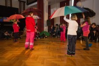 Im Interesse der Zuschauer findet der Regenschirmtanz im Saal statt, weil es draußen regnet.